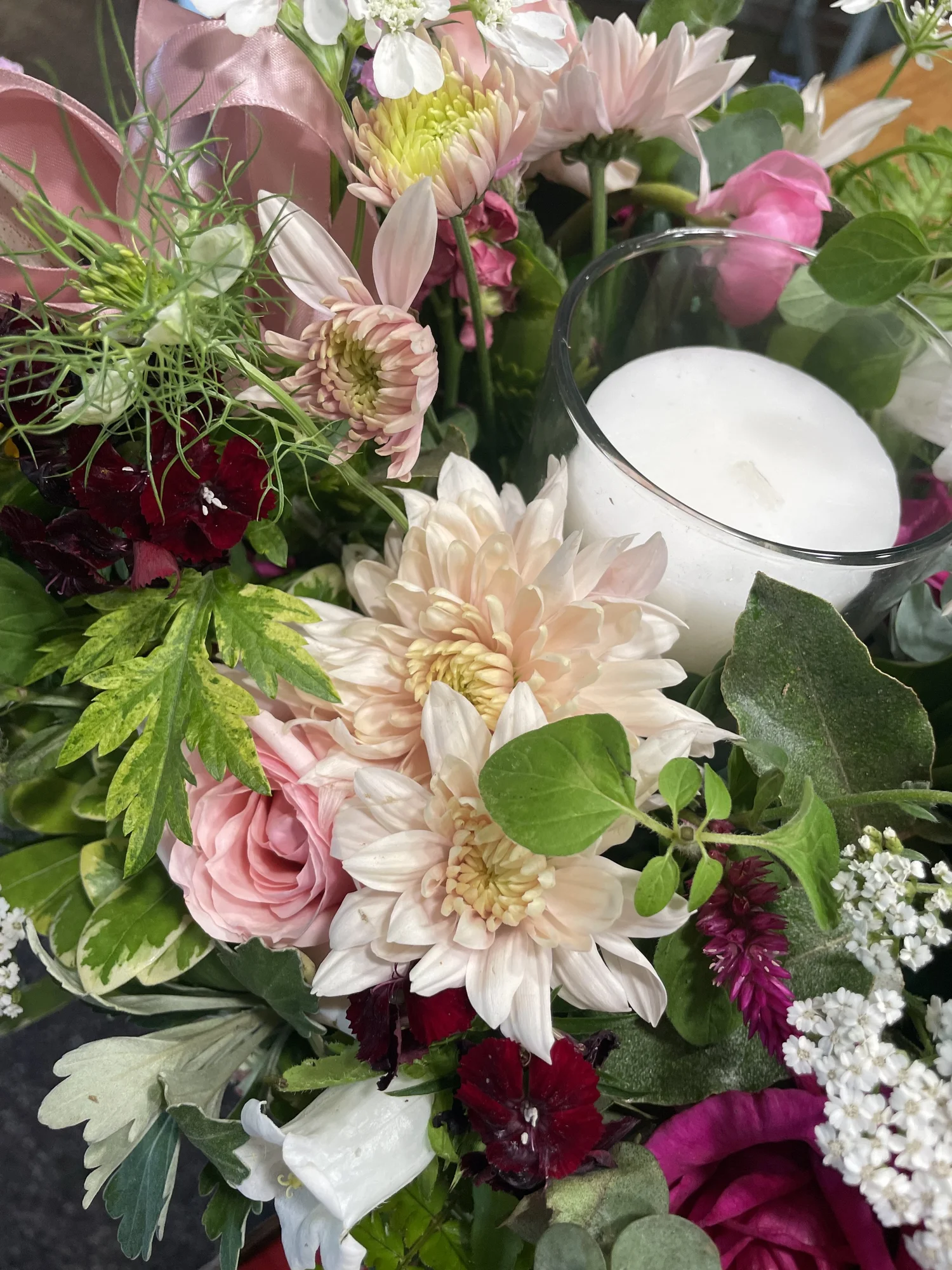 A garden centerpiece of roses and lilies around a candle