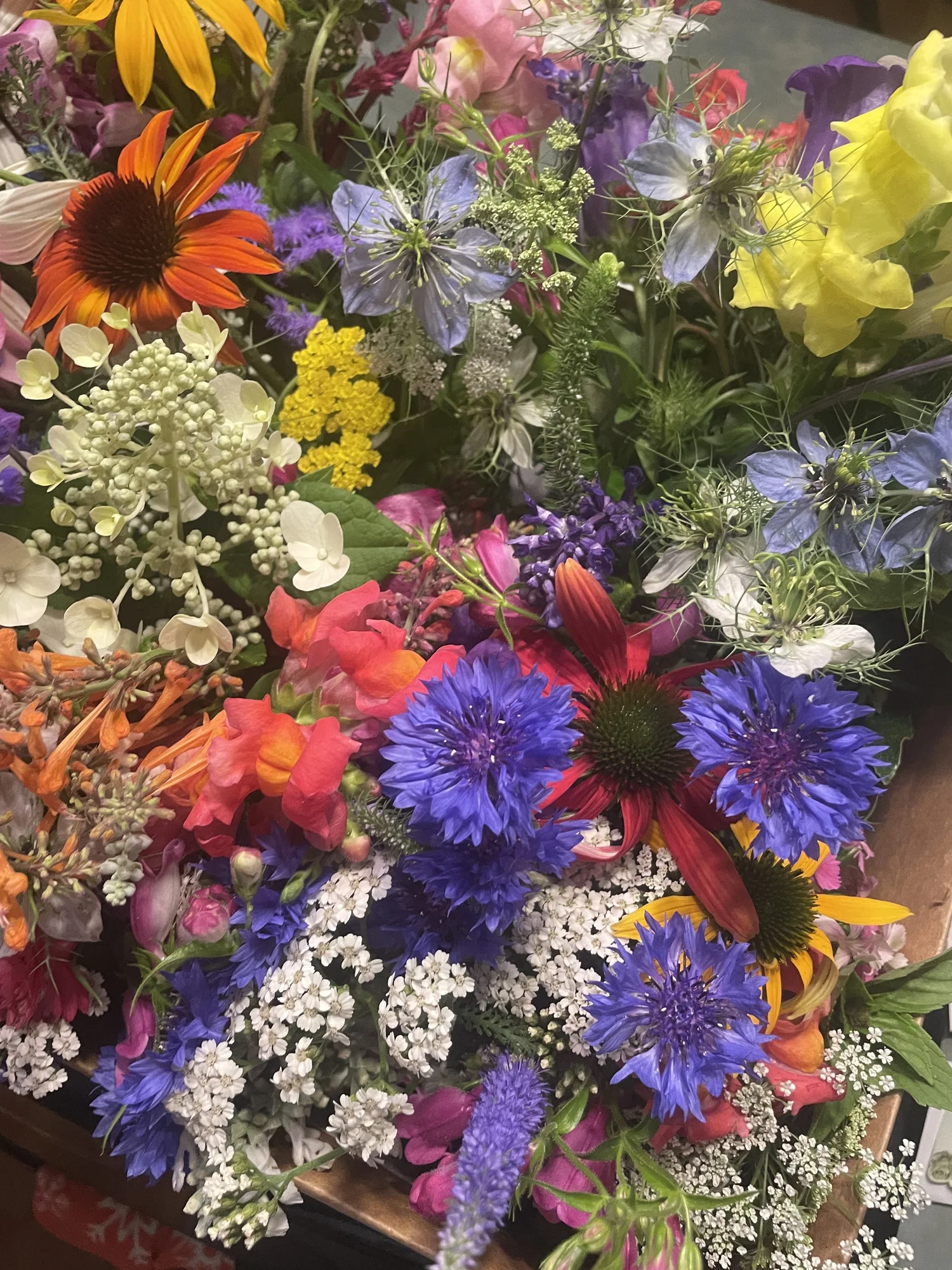 A mass of fresh-cut garden flowers in blue, orange and white